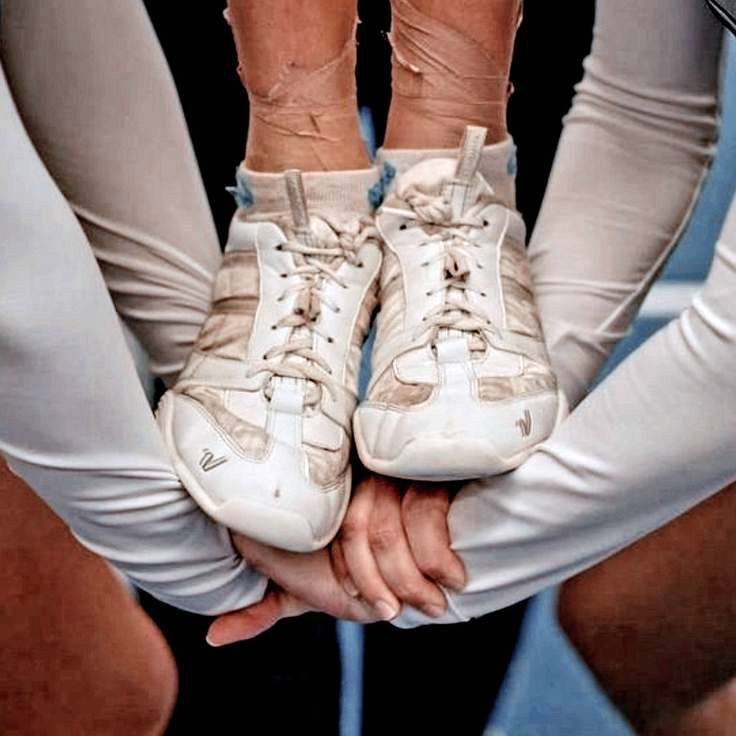 Cheerleaders holding their flyer focused on shoes